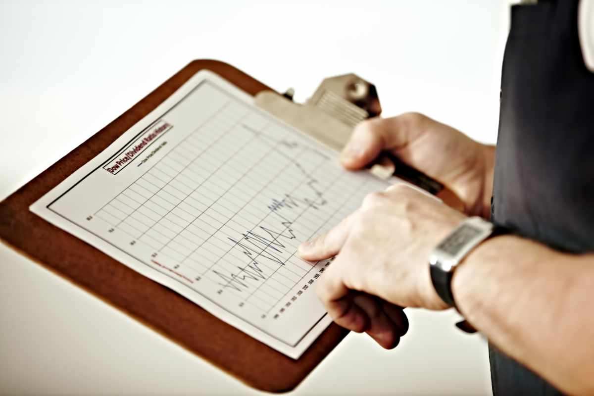 Long-term market tracking. A person pointing at a graph on a clipboard